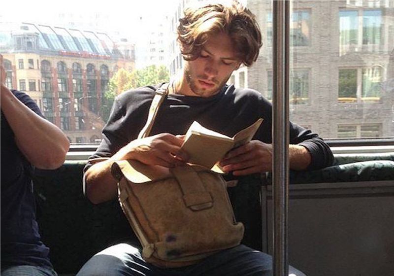 homem charmoso lendo livros no metrô de NY