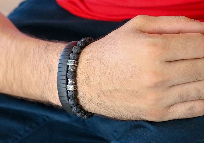 Imagem aproximada de um pulso masculino usando pulseira de pedra de lava vulcânica