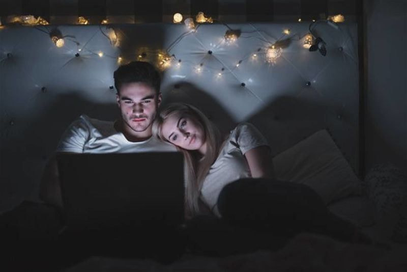 Imagem de um casal assistindo um programa no notebook