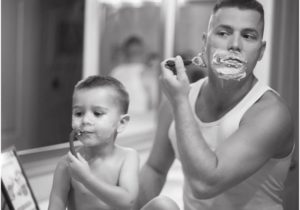 Imagem de um pai fazendo a barba acompanhado do filho