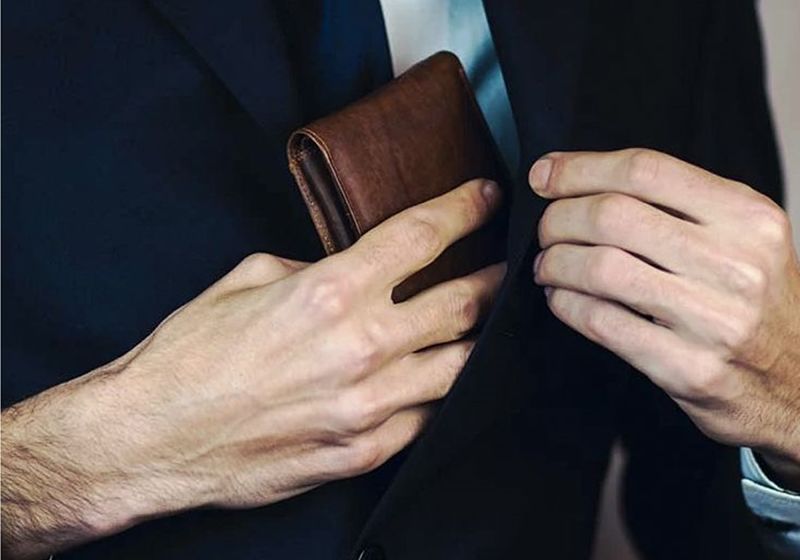Imagem de um homem guardando uma carteira no paleto