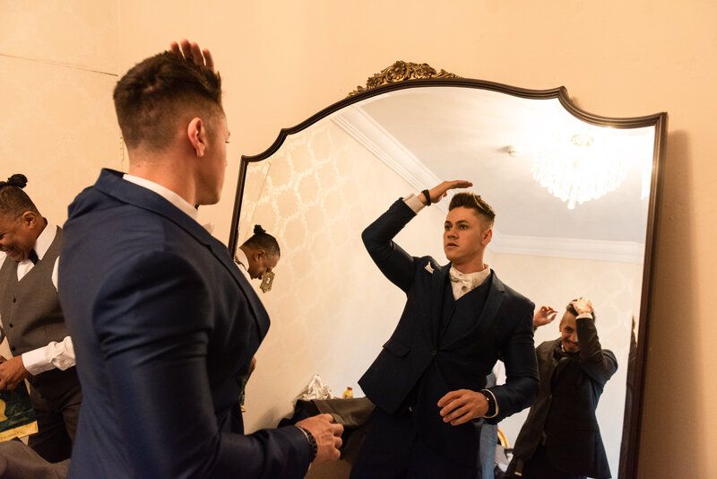 Imagem de noivo se olhando no espelho se arrumando para casamento