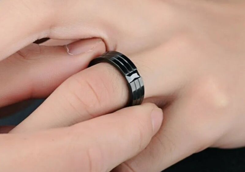 Imagem de pessoa colocando anel com pedra preta no dedo