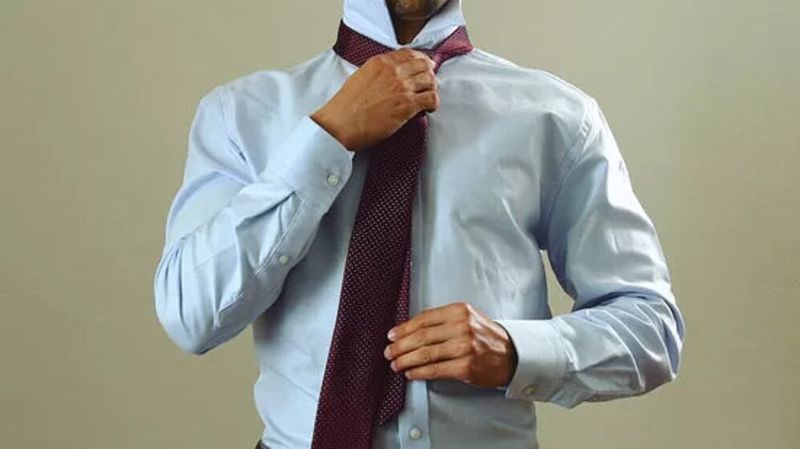Homem puxando a ponta larga da gravata para frente