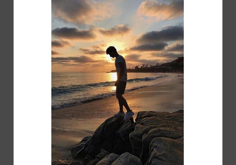 homem em cima de uma pedra na praia