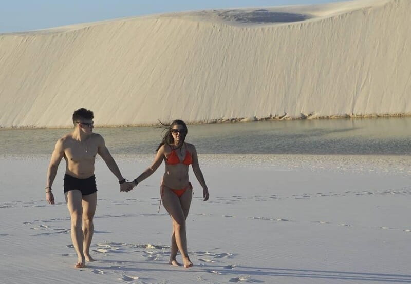 homem e mulher andando na areia da praia de mãos dadas