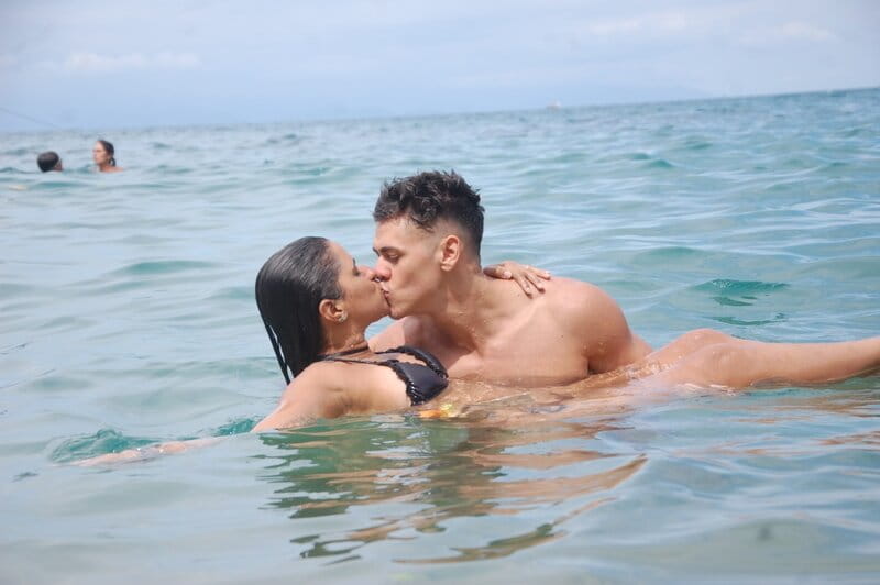 homem segurando mulher e beijando-a no mar