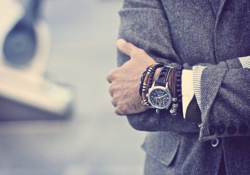 homem com os braços cruzados com pulseiras e relógios