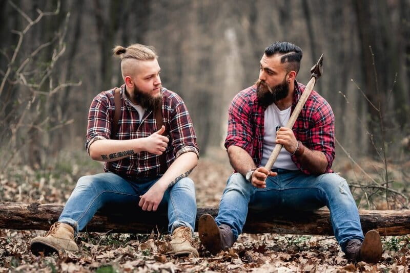 dois homens lado a lado sentado em uma madeira caida no chão